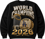 A black crewneck sweatshirt featuring a large graphic print on the front. The design displays a gold and silver championship trophy, a gold championship ring with blue and white details, and the text 'WORLD CHAMPIONS 2026' in a metallic gold and silver font.